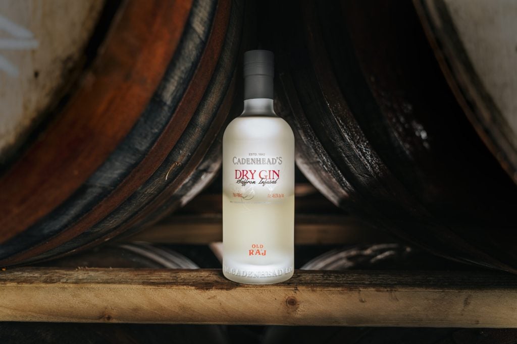 A bottle of Cadenhead's gin staged against stacked casks